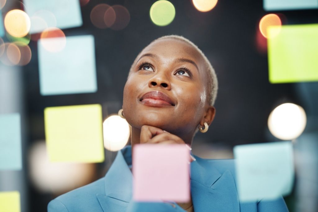 Profissional refletindo diante de painéis visuais, simbolizando o employee experience como percepção construída ao longo da jornada do colaborador e das interações no trabalho.