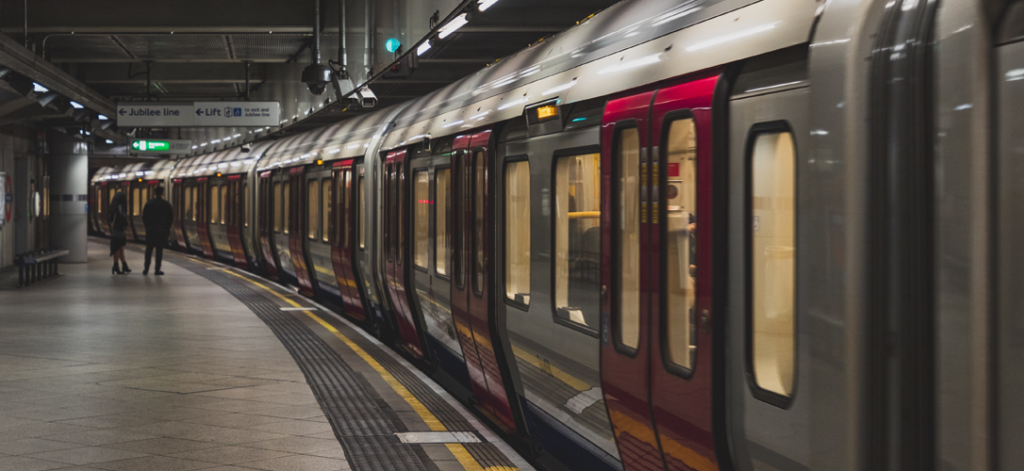 Pessoas em estação de metrô, com metrô parado ao lado, exemplificando vale transporte como benefício corporativo.
