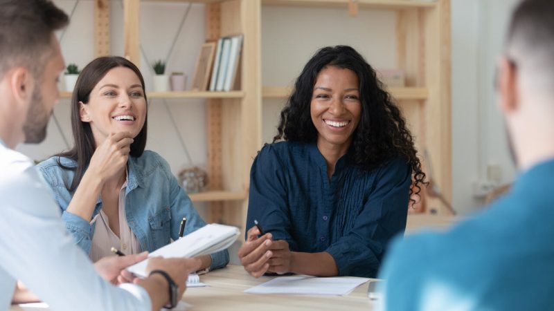 Grupo de profissionais discutindo tendências de benefícios e serviços corporativos em uma reunião, refletindo a importância da colaboração e bem-estar no ambiente de trabalho.