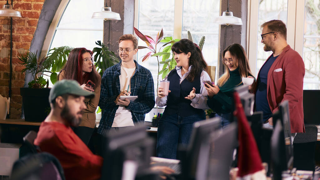 Colaboradores reunidos em ambiente de trabalho colaborativo discutindo ideias e estratégias, representando cultura organizacional e integração de equipe.